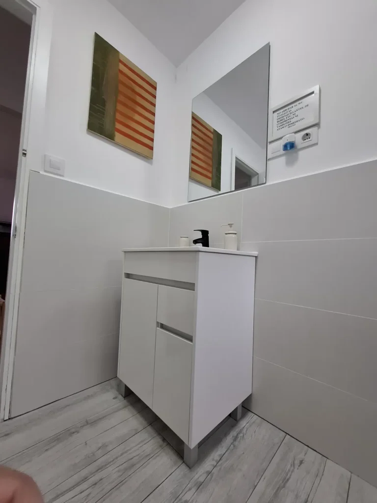 Un lavabo bajo un espejo y un cuadro decorativo