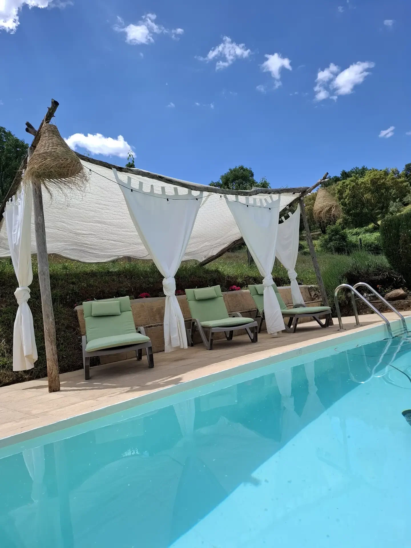 Un sombrajo con tumbonas junto a la piscina