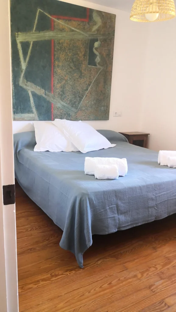 Habitación de matrimonio con una cama grande y un cuadro grande en el cabecero