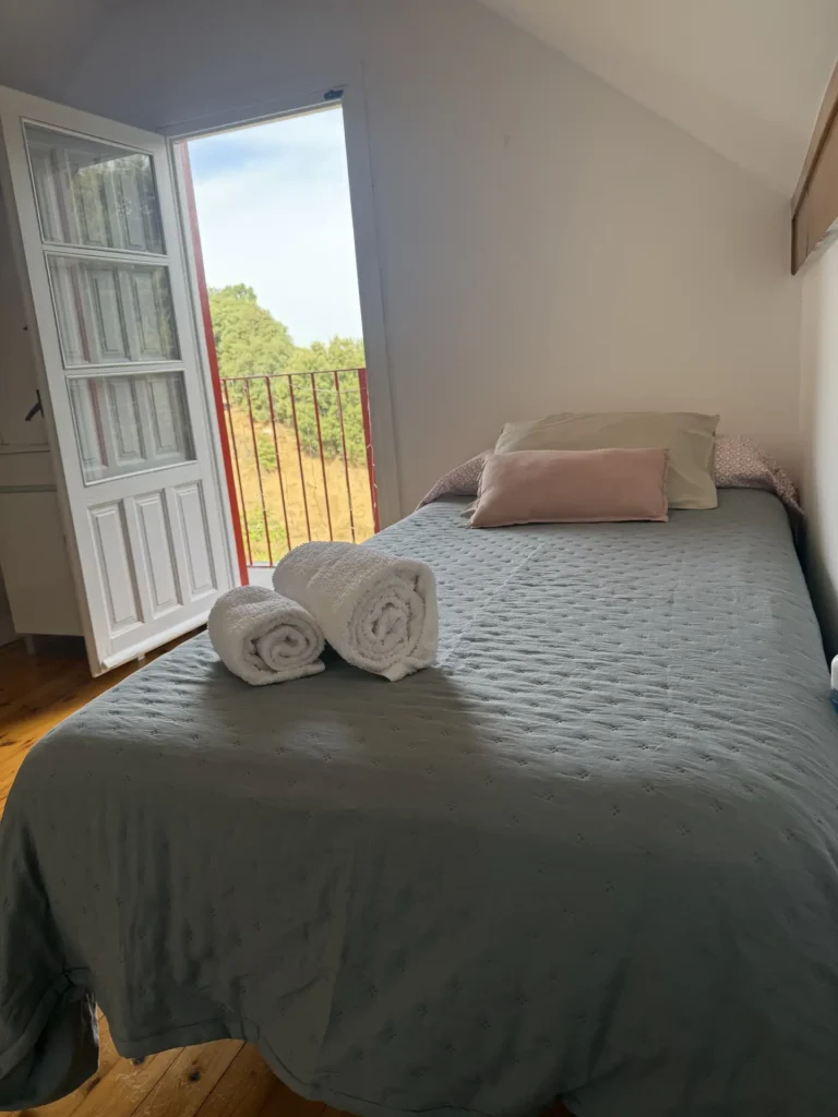 Cama en una habitación abuhardillada con salida a un balcón